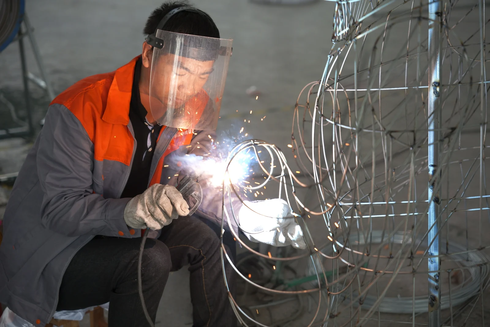 A maker welding sections of a lantern framework.
